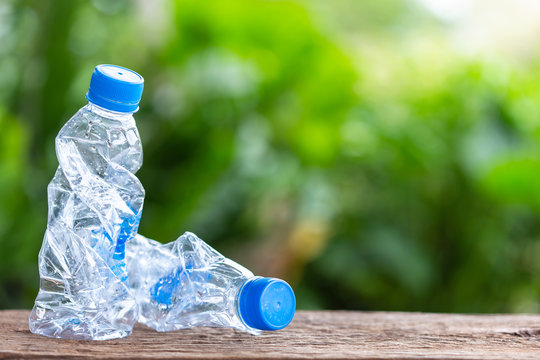 Clear empty plastic bottle on wooden table or counter with green nature light blur background