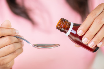 Woman hand pouring medication or antipyretic syrup from bottle to spoon. healthcare, people and medicine concept. - obrazy, fototapety, plakaty