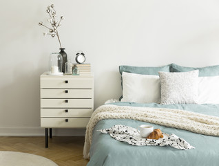 Coffee cup and croissant placed on double bed in real photo of white bedroom interior with books,...