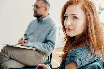 Close-up of a beautiful girl looking at the camera with a therapist in the background