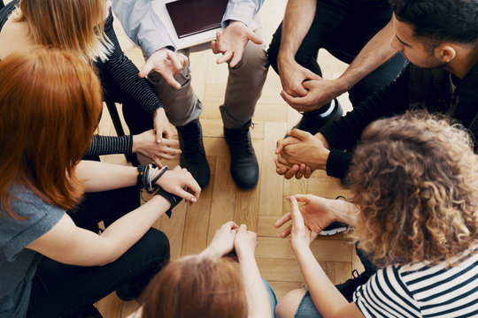 Close-up of hands of teenagers sitting in a circle during a support meeting