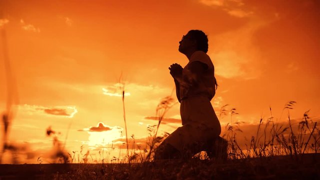 the girl prays. Girl folded her hands in prayer silhouette at sunset. slow motion video. Girl folded her hands in prayer pray to God. girl praying asks forgiveness for sins of repentance. lifestyle