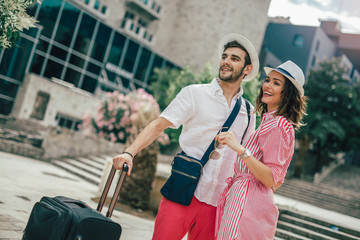 Smiling young travellers couple looking for hotel