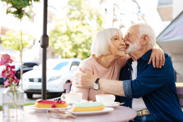 Light flirt. Cheerful senior couple flirting and sitting at cafe