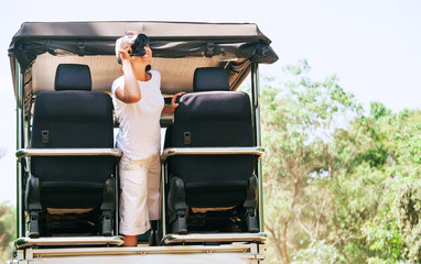 Woman photographer takes a picture with professional camera on tropical safari