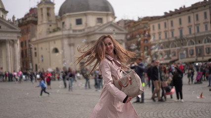 Obraz premium Pretty girl in Rome, Italy. Young lady dancing in the ancient Roman centre on the background of famous buildings. Italian square full of people