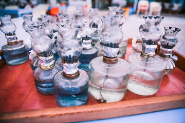 Old Oil Glass Lamps with DIY fixes gathered on Table on Greek Beach at Sunset.