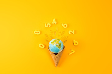top view of earth globe in waffle cone surrounded with digits on yellow