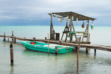 Fototapeta na wymiar Small Boat, Mooring Posts, Buoys and Overcast Tropical Sea.