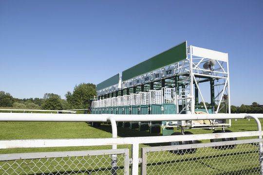 start gate trailer for the horse race on a green grass track at a sunny day against the blue sky, copy space