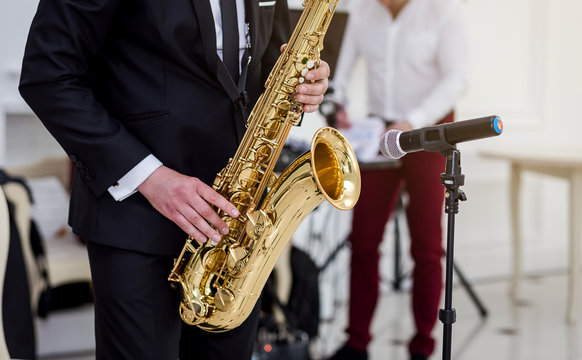Gold saxophone with specks on it in male hands