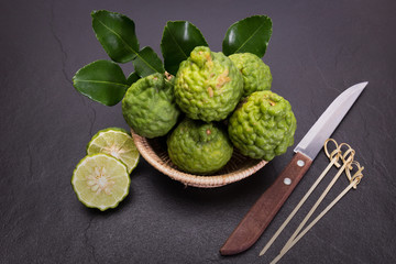 Bergamot, kaffir lime and kaffir lime leaf with basket and knife  on dark background
