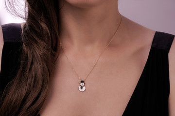 Girl wearing a gold necklace with a snowman pendant