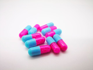 Obraz na płótnie Canvas Medication and healthcare concept. Many pink-blue capsules of Itraconazole 100 mg., used to treat infections caused by fungus. White background, selective focus and copy space.