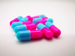 Obraz na płótnie Canvas Medication and healthcare concept. Many pink-blue capsules of Itraconazole 100 mg., used to treat infections caused by fungus. White background, selective focus and copy space.