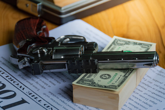 Old guns are placed on bank dollar and newspapers, on wooden table, To dark business concept.