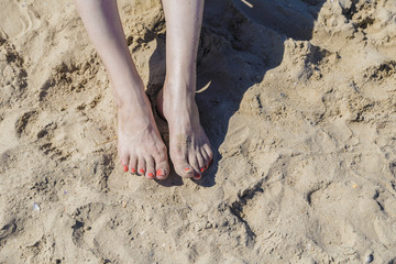 Legs on the sea sand near the sea shore on a bright sunny day.