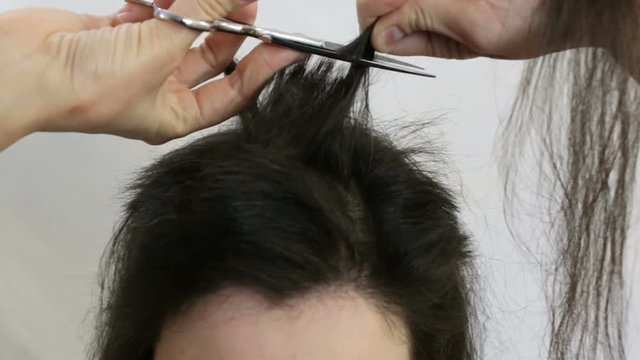 The girl cuts her long hair very short. Real time, indoors, close-up, top view
