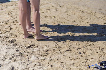 Legs on the sea sand near the sea shore on a bright sunny day.