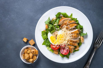 Caesar salad with chicken breast and tomatoes.