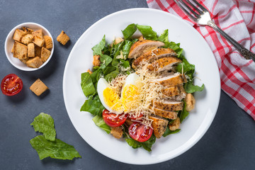 Caesar salad with chicken breast and tomatoes.
