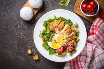 Caesar salad with chicken breast and tomatoes.