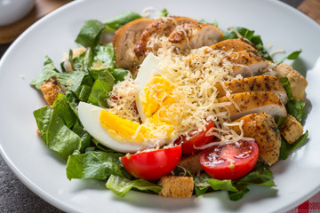 Caesar salad with chicken breast and tomatoes.
