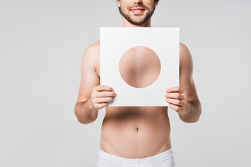 cropped shot of smiling man in underwear holding white paper circle figure isolated on grey