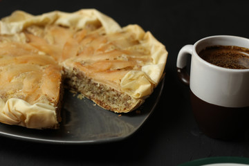 Apple cake with almond cream on a dark background. Baked cake with coffee and teaspoon.  Pie for the whole family on a sunny day
