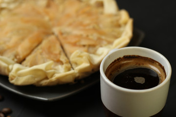 Apple cake with almond cream on a dark background. Baked cake with coffee nd coffee beans. Pie for the whole family on a sunny day