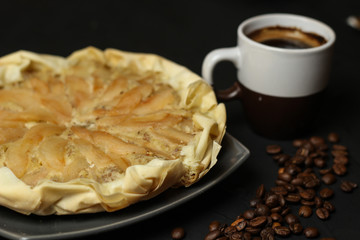 Apple cake with almond cream on a dark background. Baked cake with coffee nd coffee beans. Pie for the whole family on a sunny day