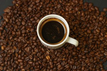 A cup of coffee with coffee beans on a dark background. A delicious fragrant coffee of the best varieties