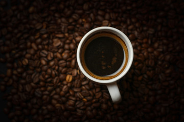 A cup of coffee with coffee beans on a dark background. A delicious fragrant coffee of the best varieties