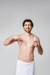 Fototapeta premium portrait of smiling man with toothpaste and toothbrush isolated on grey