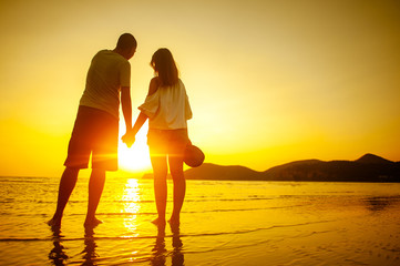 Fototapeta premium happy couple running to the sea at sunset beach.