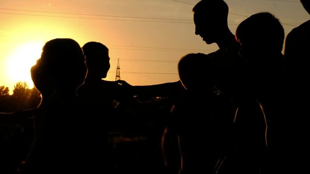 Silhouettes of young boys, jogging on a training against the sunset
