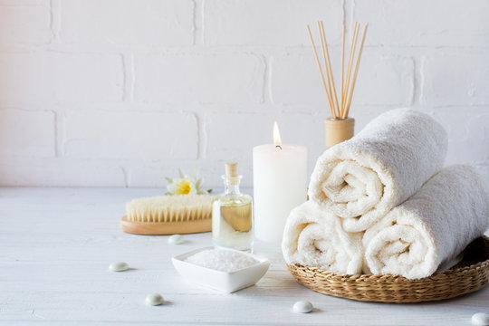 SPA aromatherapy background.  Still life with white towel, bath oil, massage brush and candle.