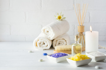 Spa still life with towel,white lily, sea salt, bath oil, sugar body scrub and candle