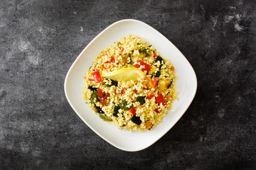 Couscous with vegetables on black stone. Top view. 