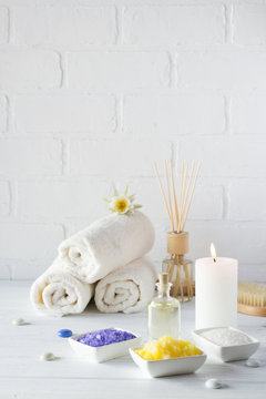 Spa still life with towel,white lily, sea salt, bath oil, sugar body scrub, massage brush and candle