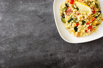 Couscous with vegetables on black stone. Top view. Copyspace