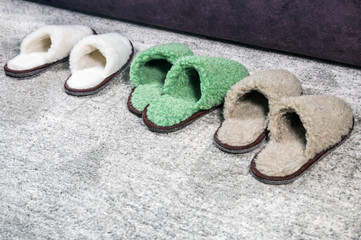 many Slippers of different size and color on the carpet