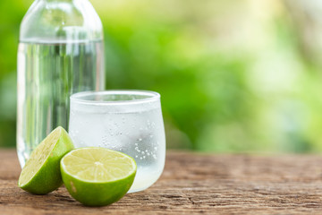 Glass of iced lemon soda on wooden table with green blur space for text or design