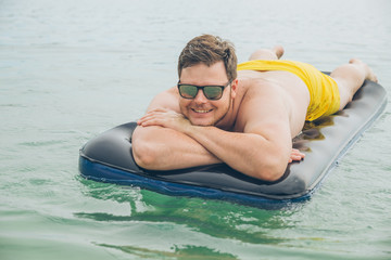 man swimming on mattress in sea