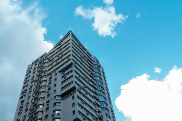 A pointed high-rise building against the background of a bright blue sky. A tall building with many windows and balconies.
