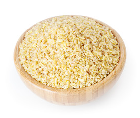 Uncooked bulgur in wooden bowl isolated on white background with clipping path