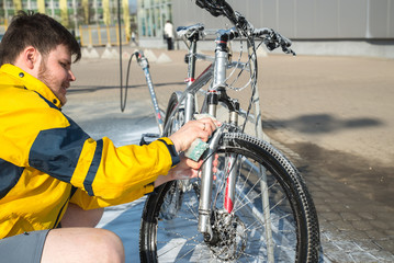 young man clean bicycle with soap and sponge at carwash self-service. lifestyle
