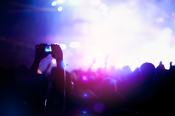 silhouettes of hand in concert.Light from the stage.