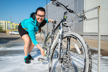 young sport woman washing bicycle at self-service car wash