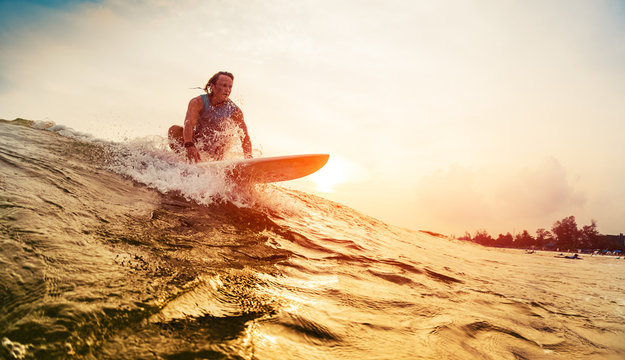 Young surfer rides the wave during sunset